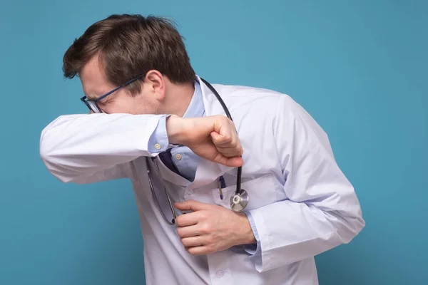Ung kaukasisk läkare hosta i armbågen är sjuk — Stockfoto
