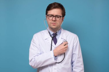 Kafkasyalı genç doktor steteskop tutuyor ve kalbini dinliyor.