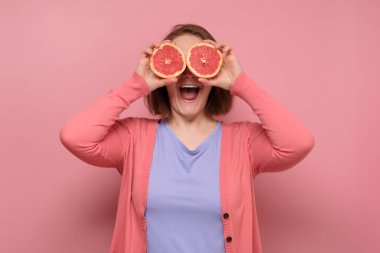 Güzel kız yüzüne bir dilim greyfurt tutarak gülümsüyor.
