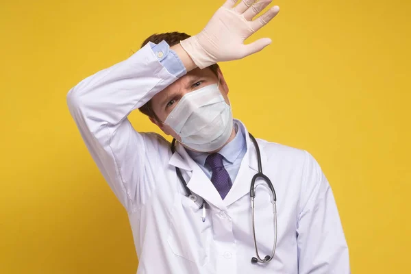 Uomo medico cercando stressato e stanco dopo il lavoro contro sfondo giallo — Foto Stock