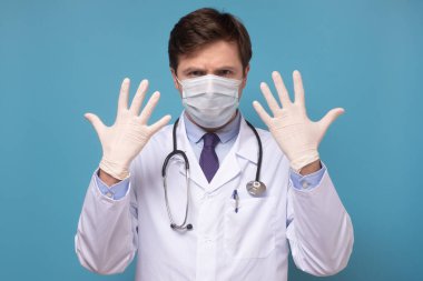 Mavi arka planda steril lateks eldiven giyen Kafkasyalı olgun bir adam..