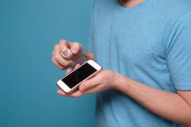 Kafkasyalı bir adam şişeden dezenfekte ederek akıllı telefonunu dezenfekte ediyor..