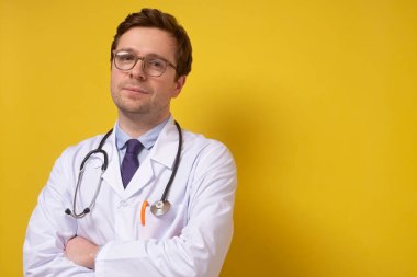 Gülümseyen olgun beyaz doktor sarı duvarda izole edilmiş..