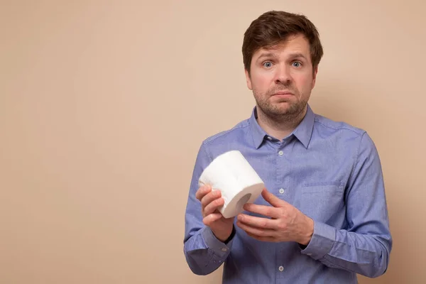 Joven triste caucásico hombre agujero un rollo de papel higiénico . —  Fotos de Stock