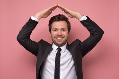 Beyaz takım elbiseli genç adam ev jesti gösteriyor. Coronavirus karantinası ya da evde kalmak anlamına geliyor. Covid-19 ev izolasyonu