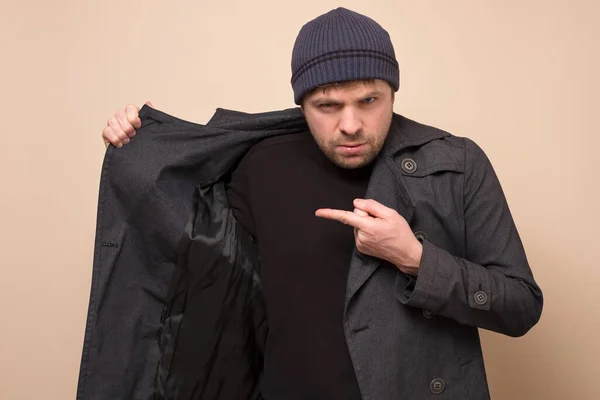 Junger kaukasischer Spekulant-Mann deutet auf seinen Mantel auf leeren Platz, in dem sich Mangelnahrung versteckt. Wollen Sie es kaufen? Defizit in Geschäften wegen Coronavirus-Panik — Stockbild Junger Kaukasischer Spekulant Mann Deutet Auf Seinen Mantel Auf Leeren — Stockfoto