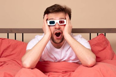 Genç, beyaz bir adam evinde, yatağında 3 boyutlu gözlüklerle televizyon izliyor, heyecanlanıyor ve eğleniyor. Stüdyo çekimi
