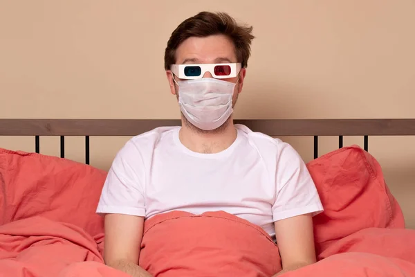 Hombre Joven Máscara Médica Gafas Viendo Televisión Casa Cama Permanecer —  Fotos de Stock