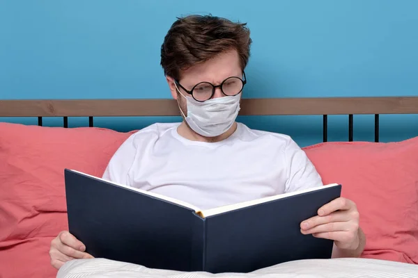 Biały Młodzieniec Okularach Masce Medycznej Czytający Powieść Sypialni Samotny Kwarantannie — Zdjęcie stockowe