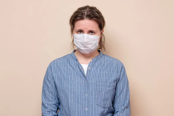 青い縞模様のシャツを着たコロナウイルスのパンデミックのために強調された医療用マスク感の若い女性を強調した スタジオショット — ストック写真