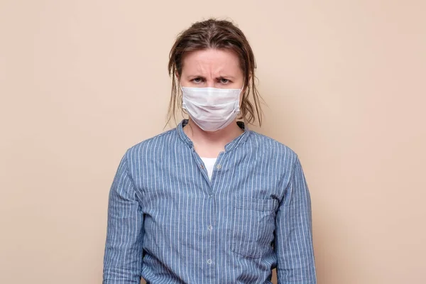 青い縞模様のシャツを着たコロナウイルスのパンデミックのために強調された医療用マスク感の若い女性を強調した スタジオショット — ストック写真