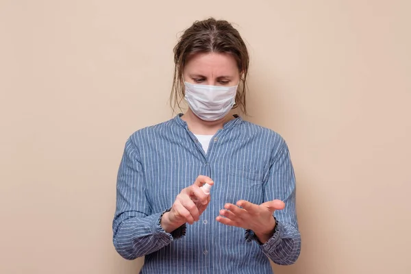 若い女性は自分自身をウイルスから守る消毒剤で手を噴霧します スタジオショット — ストック写真