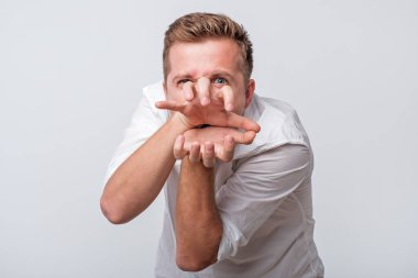 Çılgın genç adam parmaklarıyla canavar dişleri gösteriyor..