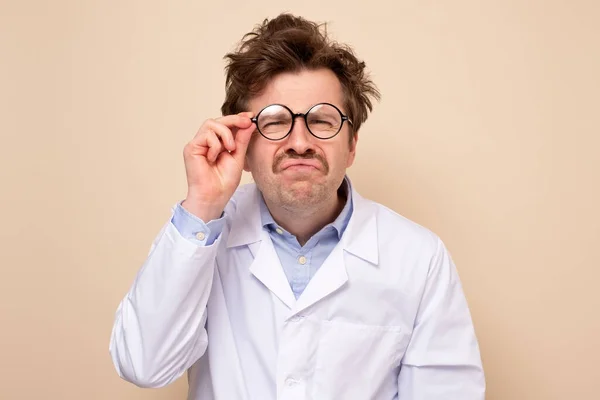 doctor man curves lower lip being confused, looks displeased through glasses
