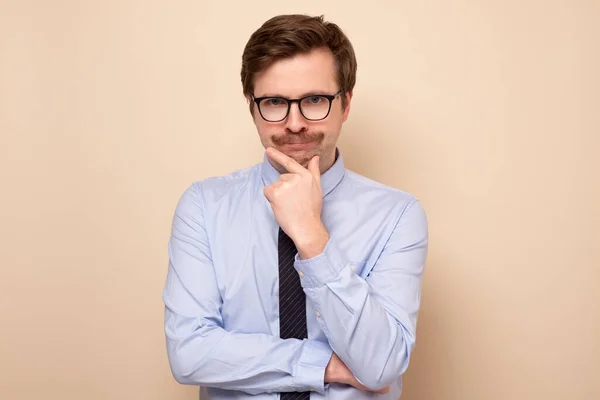 Man in glasses with his finger to his chin looking u with a pensive expression. — Stock Photo, Image