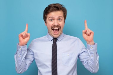 Bıyıklı iş adamı yukarı bakıyor ve kameraya gülümsüyor.