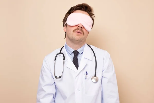 Giovane uomo medico esausto in maschera di sonno dopo dura giornata Worlking — Foto Stock