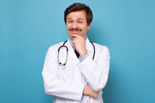하얀 가운을 입고 웃으면서 턱을 문지르는 의사 — 스톡 사진