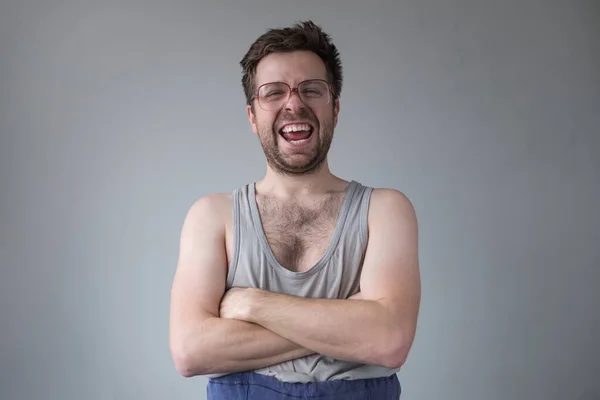 근사하지 않은 옷차림의 남자가 큰 안경을 쓰고 웃으면서 집에 혼자 있는 것에 미쳐 가는 모습. — 스톡 사진