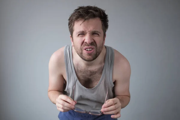 Giovane ragazzo con i capelli disordinati strabismo guardando sospettosamente come se il controllo se reale — Foto Stock