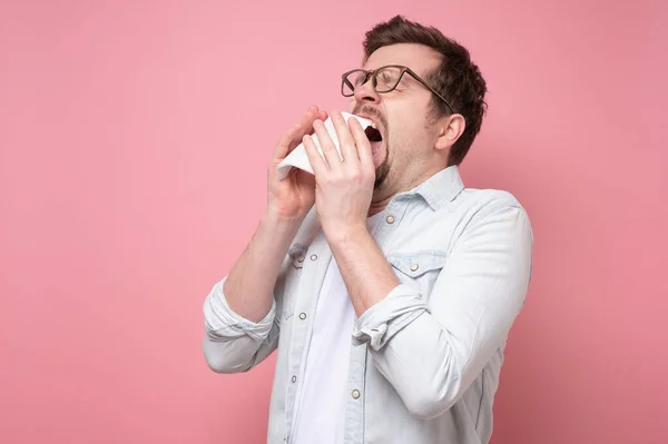 Hombre con pañuelo y gafas estornudando estando enfermo o con alergia —  Fotos de Stock