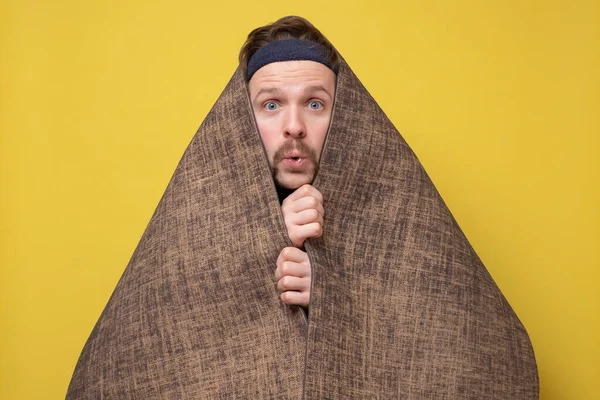 Un uomo spaventato divertente si nasconde con un tappetino da yoga — Foto Stock