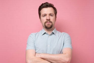 Sakallı genç adam kameraya ciddi ciddi bakıyor..