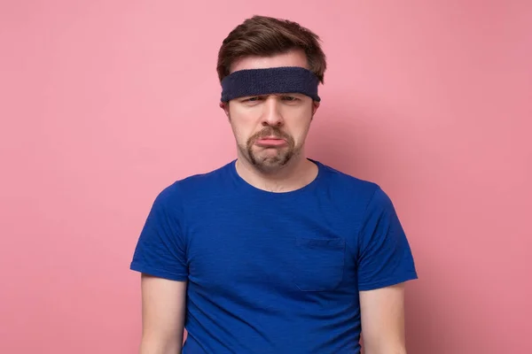 Junger kaukasischer Sportler mit Stirnband, der gelangweilt und müde ist und einen entspannten Tag braucht. Studioaufnahme auf rosa Wand — Stockbild Junger Sportler, der gelangweilt und müde ist und einen entspannten Tag braucht. — Stockfoto