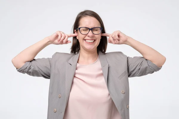Zralá žena v brýlích s nespokojeným vzhledem ucpává si uši podrážděné hlukem — Stock fotografie