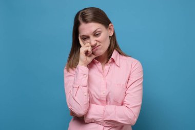 Düşünceli, genç bir kadın. Düşüncelere dalmış, planlı bir problem çözümü. Fikir olarak düşün. Stüdyo resmi mavi duvarda.