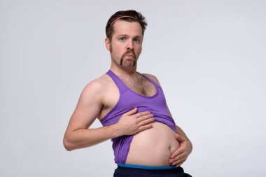 Koca göbekli şişman ve komik genç adam çekirdek egzersizleri yapmak için can atıyor. Diyet kavramı.