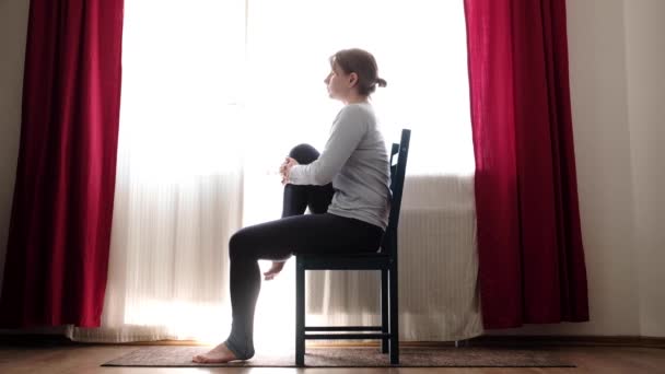 Femme faisant de l'exercice d'étirement en utilisant une chaise au salon . — Video