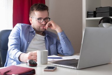 Evde dizüstü bilgisayarla çalışan beyaz bir adam.