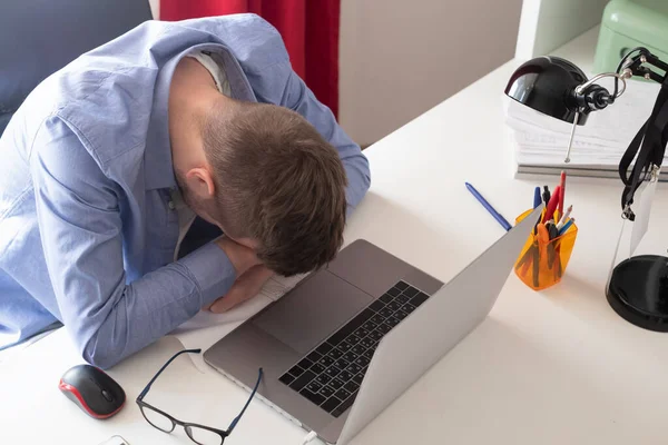frustrated male self employee working on laptop computer at home being tired.