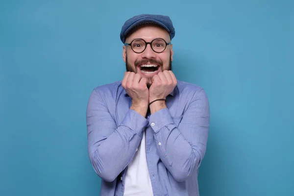 Homem caucasiano animado com óculos e chapéu azul sendo animado recebendo ótimas notícias — Fotografia de Stock