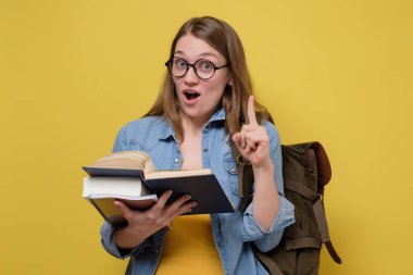 Çekici genç bir üniversite öğrencisi bir yığın kitap taşıyor..