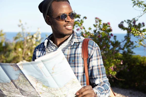 Dark-skinned male traveler holding road map