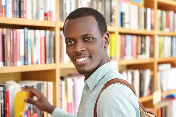 African man picking book from shelve