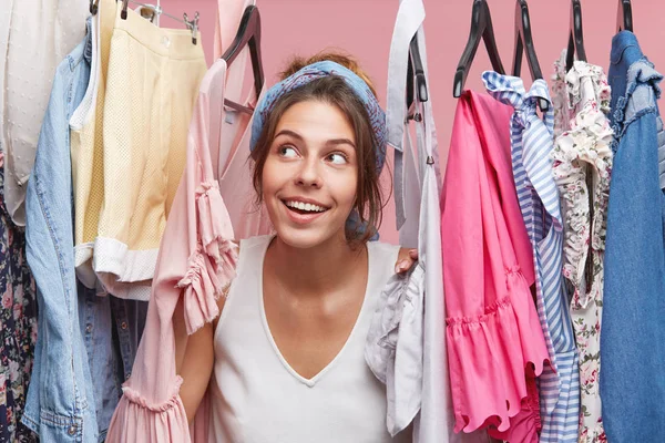 Cute female looking through hangers with clothes