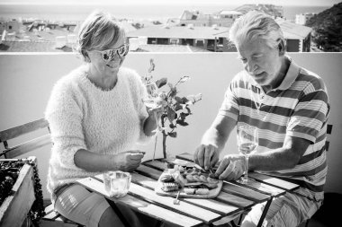 iki üst düzey yetişkin, kahvaltı veya brunch açık teras. meyve ve sebze yemek ve şarap içmek. muhteşem manzaralı çatı üzerinde boş zaman etkinliği