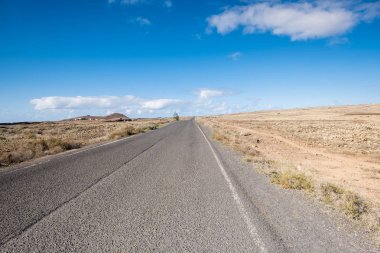 Fuerteventura içinde güzel bir manzara ile seyahat kavramı. Çöl ortasında ıssız uzun bir yol ile. Kolay yaşam doğanın keyfini