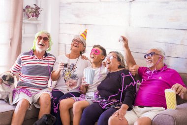 bir grup yaşlı adam beyaz saç, iki erkek, iki kadın, bir çocuk ve iki küçük pugs ile birlikte vakit geçirmek. Oynamak ve gülmek kılık ve renkli maskeleri evde