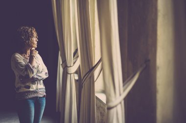 güzel kadın bakmak dışında eski bir evde ışıkla yüzünde.