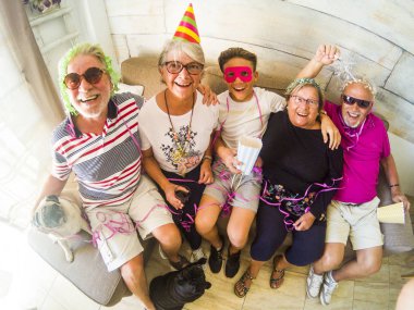 bir grup yaşlı adam beyaz saç, iki erkek, iki kadın, bir çocuk ve iki küçük pugs ile birlikte vakit geçirmek. Oynamak ve gülmek kılık ve renkli maskeleri evde