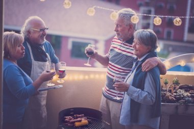 Barbekü barbekü birlikte diğer binalar üzerinde güzel manzaralı çatıdaki partisi yapacak arkadaşlar yaşlılar grubu. Ampul ışıkları Teras ve gülümseme eğleniyor. İki çiftler lesiure eldery kavramı. Vintage filtre.