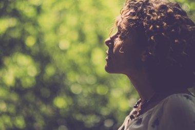 güzel bir kadın onun önünde bir yeşil doğal bokeh arka planda ile seyir için sıcak tonları