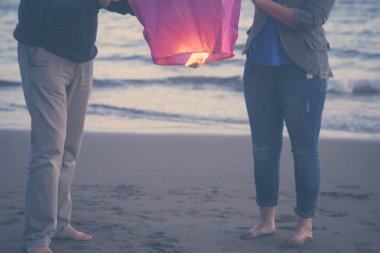 Çift birlikte sonsuza kadar rüya ve bazı arzuları, kırmızı Çin fener okyanus arka planda ile akşam gökyüzünde uçmak dilek. tatil, aşk kavramı plaj boş zaman etkinliği