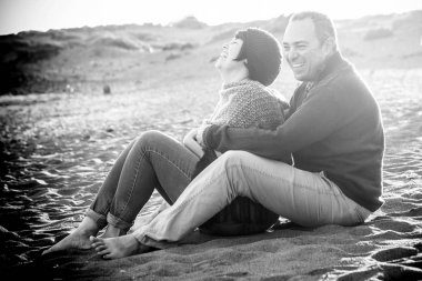 sevimli erkek ve kadın orta eğleniyor aşık açık plajda yaşlı. boş zaman etkinliği ve kocaman bir gülümseme ve gülmek hanımefendi için. adam onu kucaklamak. kayaların üzerinde arka plan