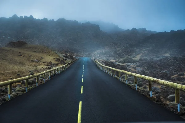 真ん中の黄色い線と霧と霧の道 山の雲には アスファルトが侵入します 神秘的なシーン — ストック写真