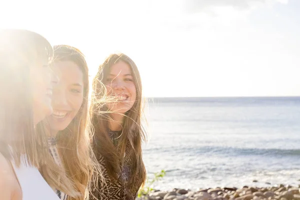 三名年轻女性朋友在特内里费海滩附近的墙上散步 用黄色的太阳在蓝天下享受假期 手牵手 — 图库照片